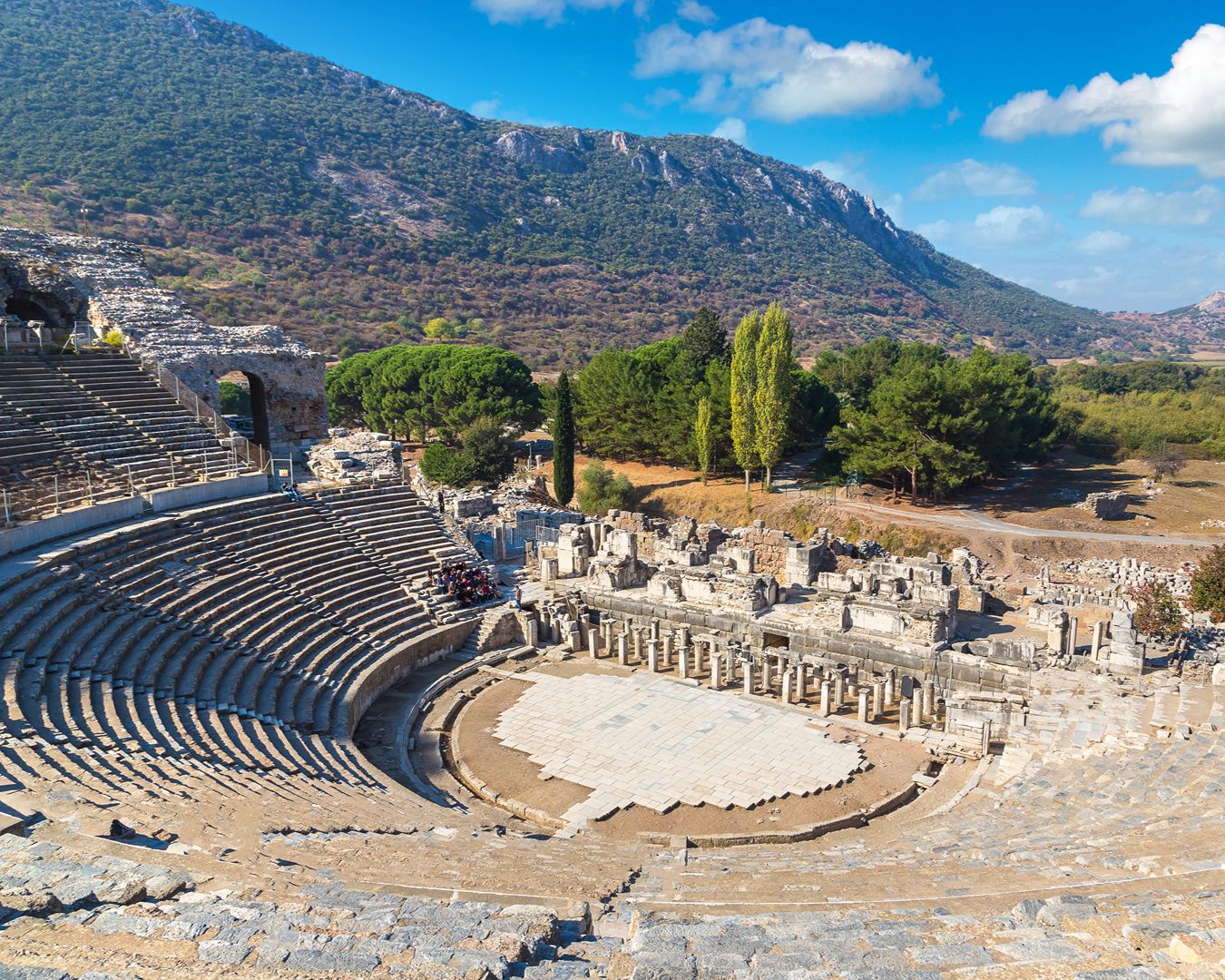Vista panorâmica do antigo Grande Teatro de Éfeso com arquibancadas de pedra e montanhas ao fundo, Turquia.
