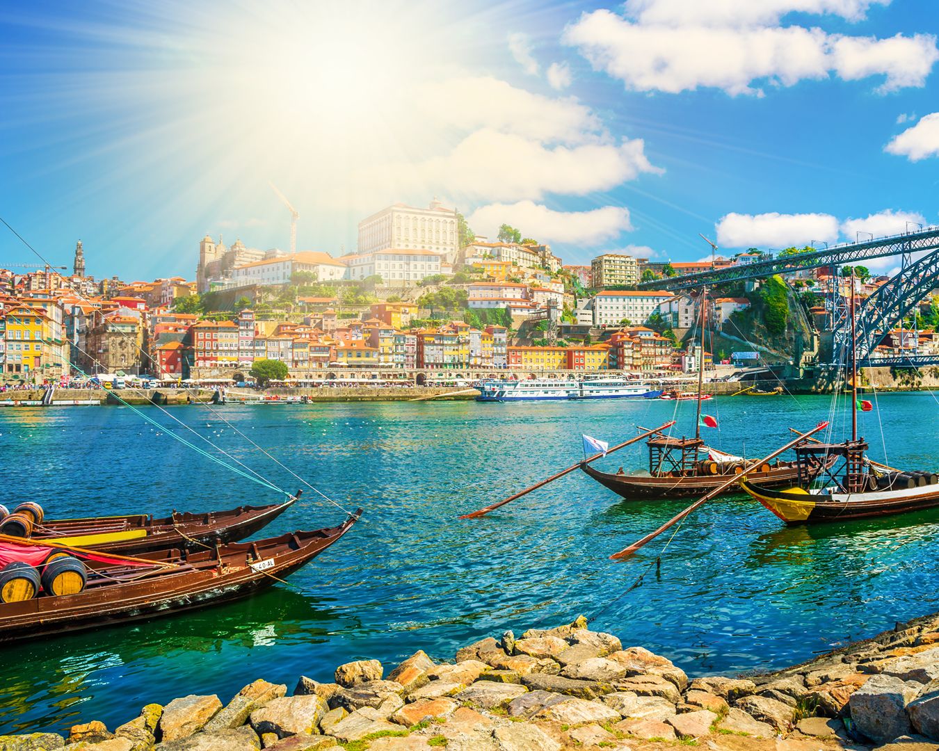 Vista do Rio Douro no Porto com barcos rabelos tradicionais, Ponte Dom Luís I e casas históricas da Ribeira.