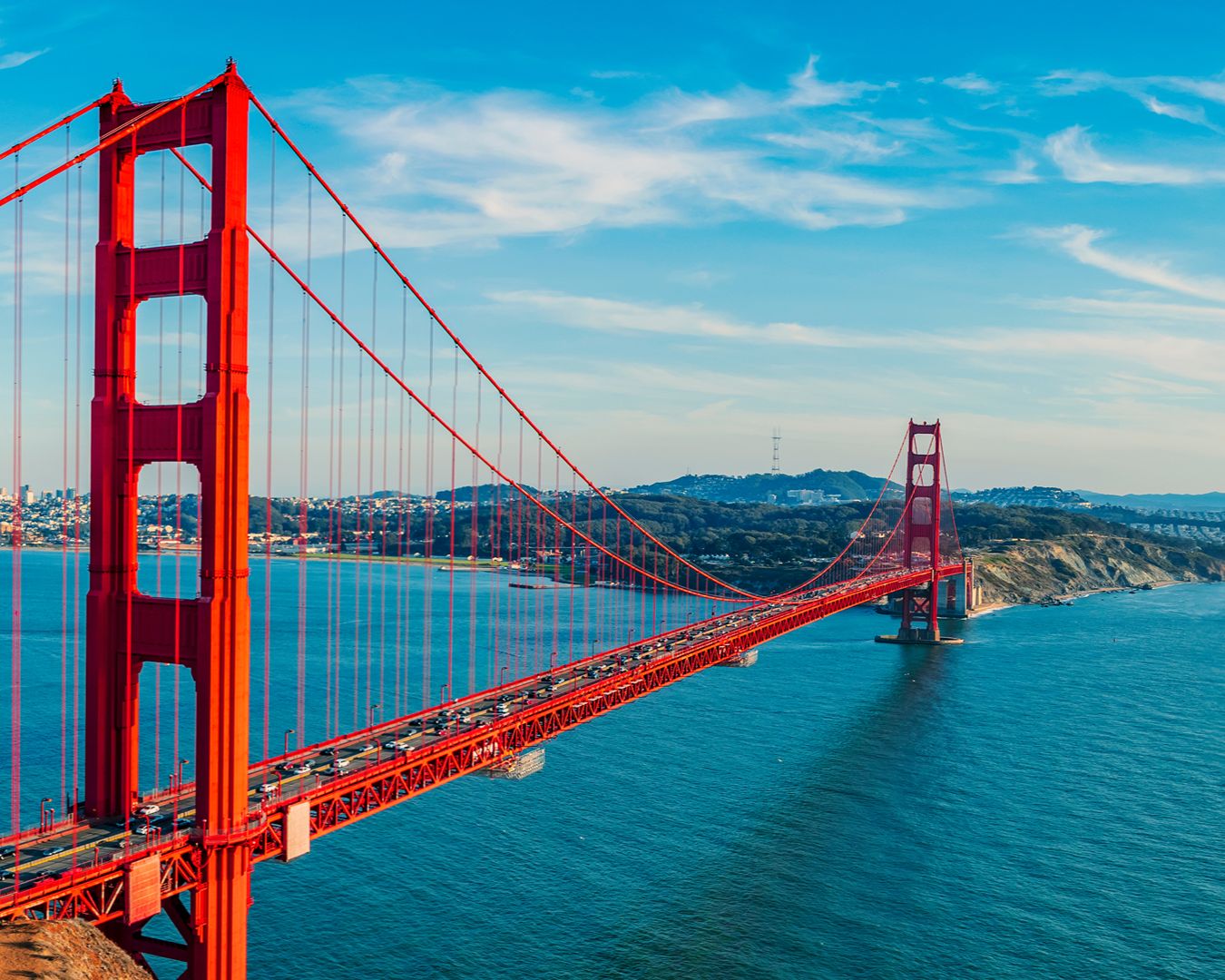 Vista panorâmica em ângulo elevado da icônica ponte vermelha Golden Gate ligando a baía de San Francisco sob céu azul.