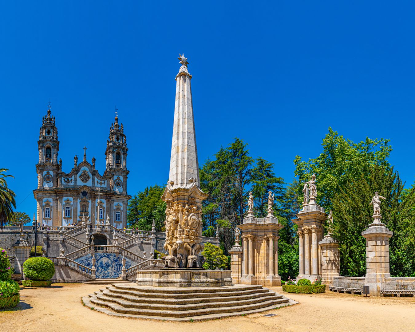 Santuário de Nossa Senhora dos Remédios em Lamego com monumentos de pedra, escadaria barroca e jardins sob céu azul.