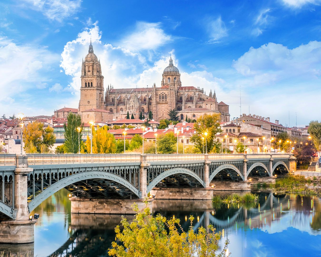 Vista da Catedral de Salamanca e da Ponte Romana refletidas no Rio Tormes ao entardecer na Espanha.