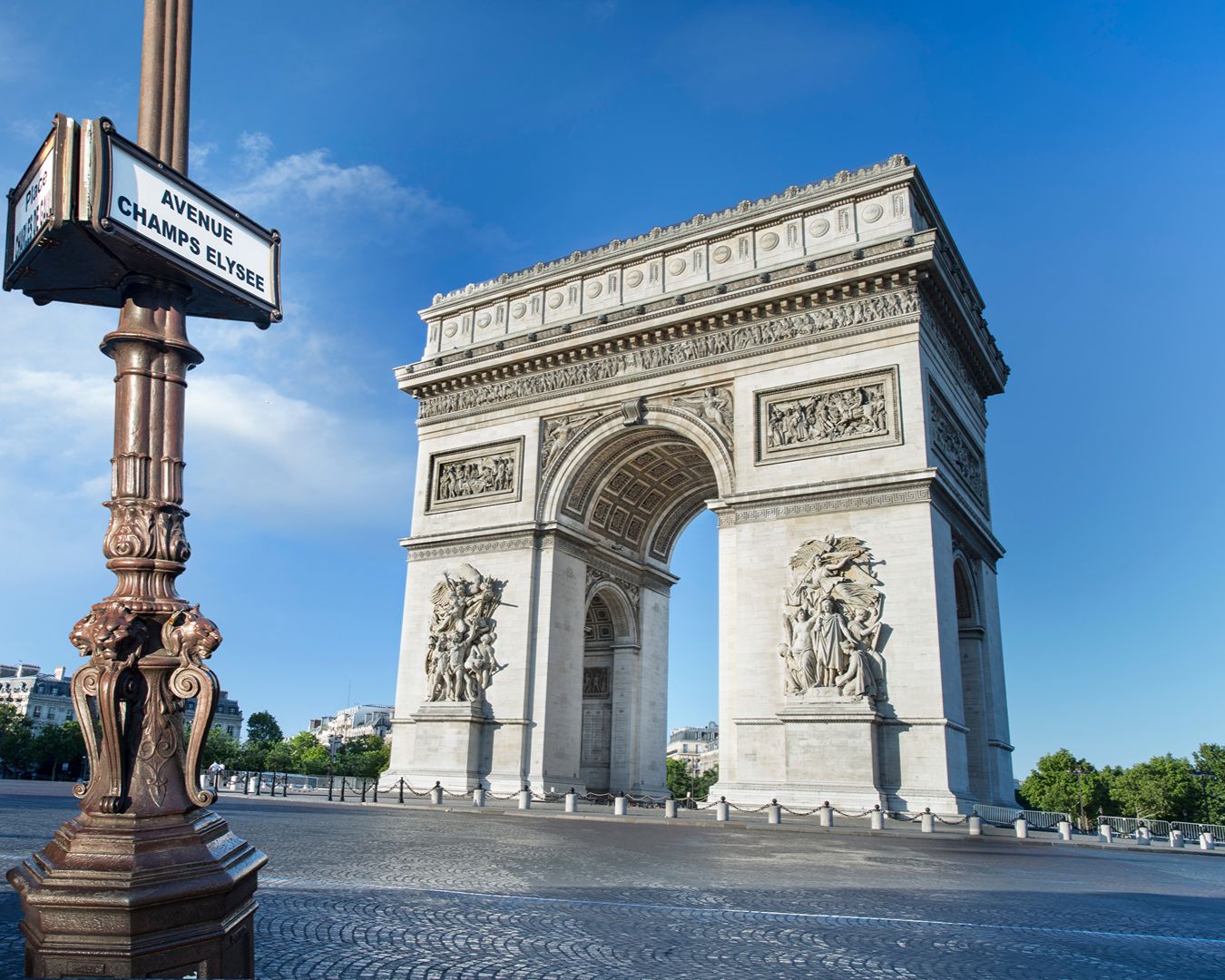 Arco do Triunfo em Paris com placa da Avenida Champs-Élysées em primeiro plano
