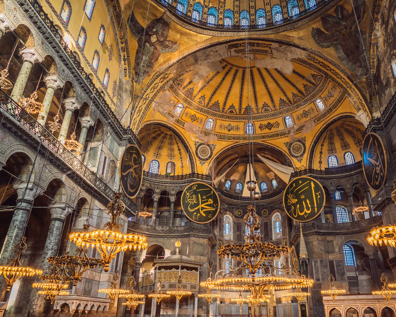 Vista do interior da Mesquita de Santa Sofia em Istambul com a cúpula principal e medalhões caligráficos islâmicos.