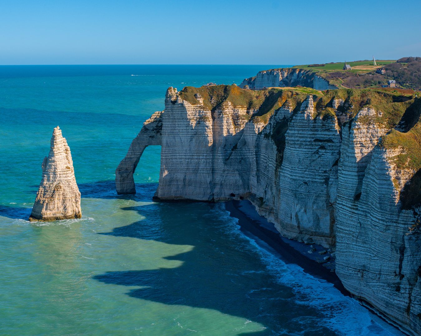 Famosas falésias de calcário branco e arco natural de Étretat com o mar azul da Normandia