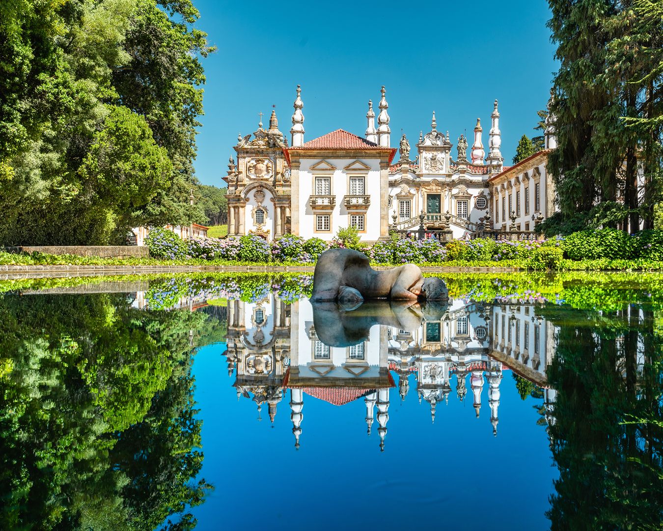 Palácio de Mateus em Vila Real com arquitetura barroca refletida no espelho d'água dos jardins.