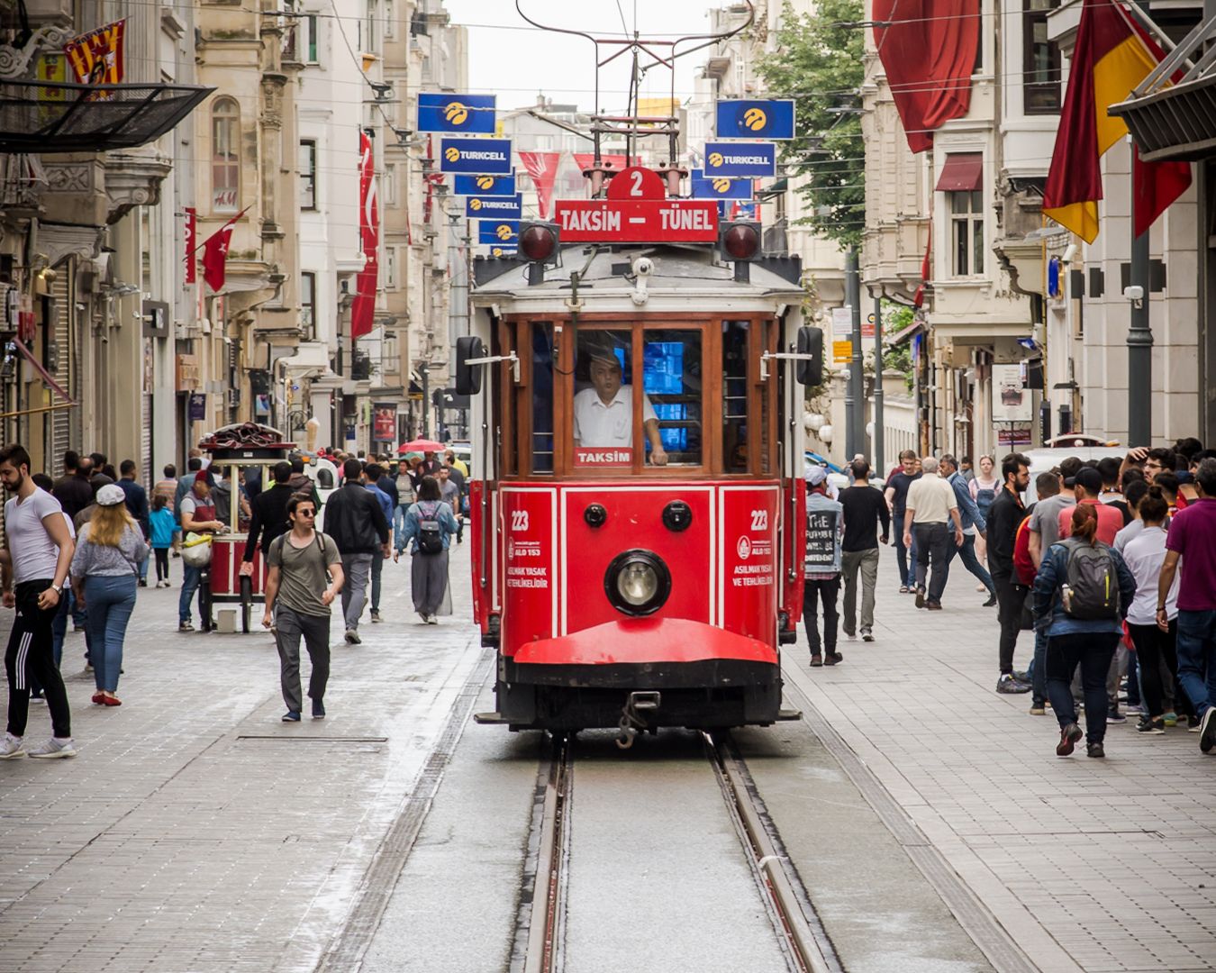 Elétrico histórico vermelho a percorrer a zona pedonal da Avenida İstiklal em Istambul, Turquia.