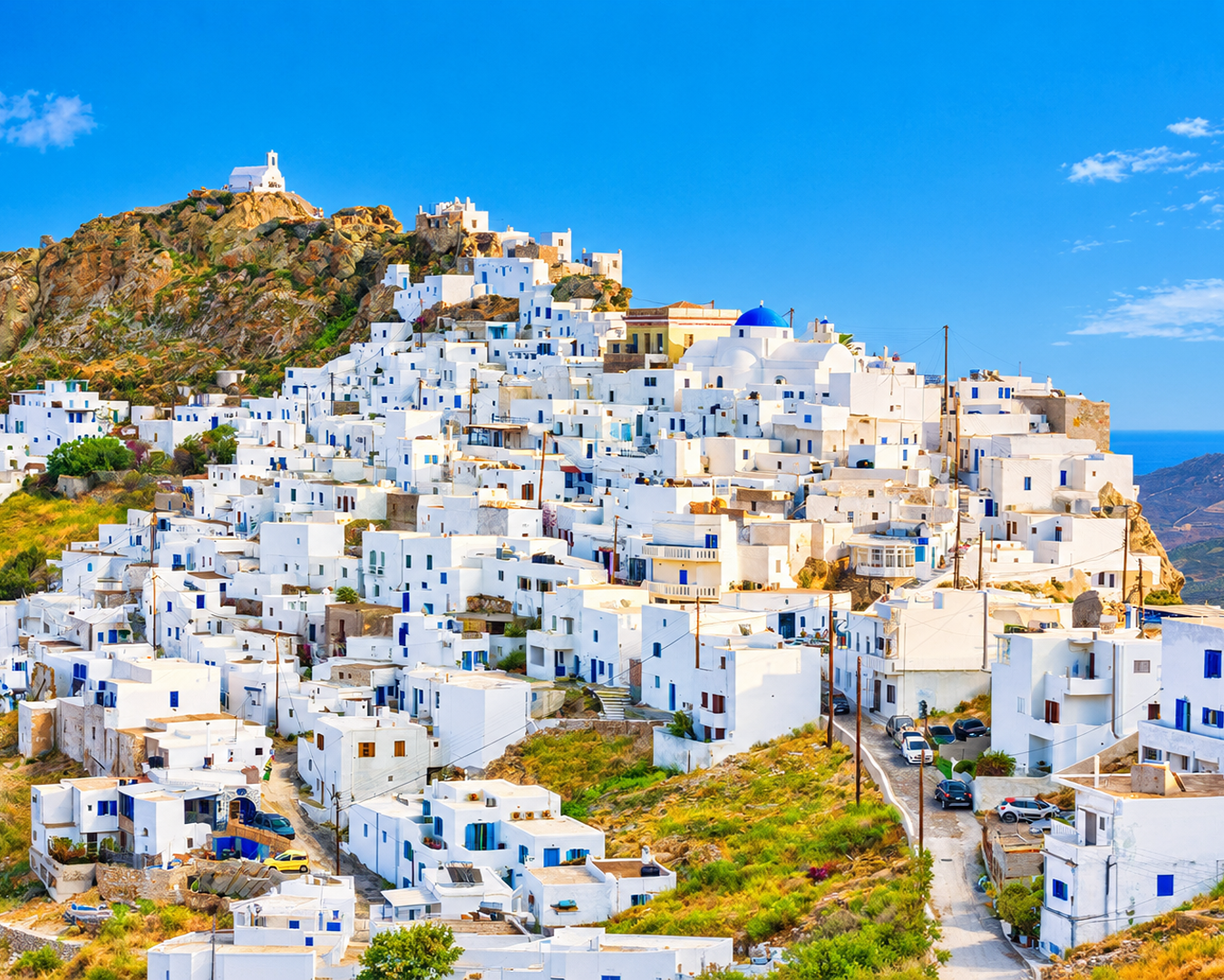 Casas brancas tradicionais com detalhes em azul construídas nas colinas de uma ilha grega com vista para o mar