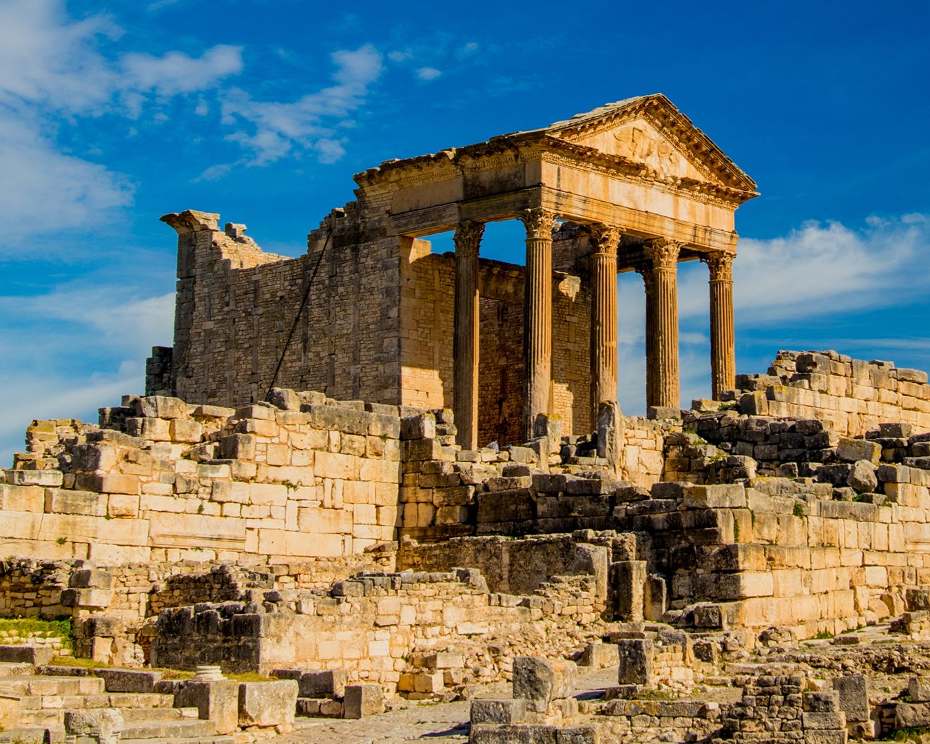 Templo romano do Capitólio preservado com colunas de pedra e ruínas arqueológicas em Dougga, Tunísia
