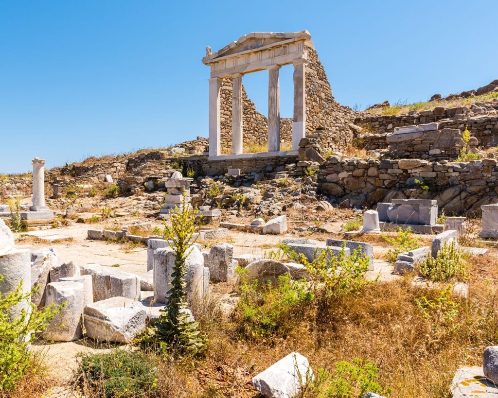 Ruínas de templo antigo com colunas de mármore e frontão no sítio arqueológico da Ilha de Delos
