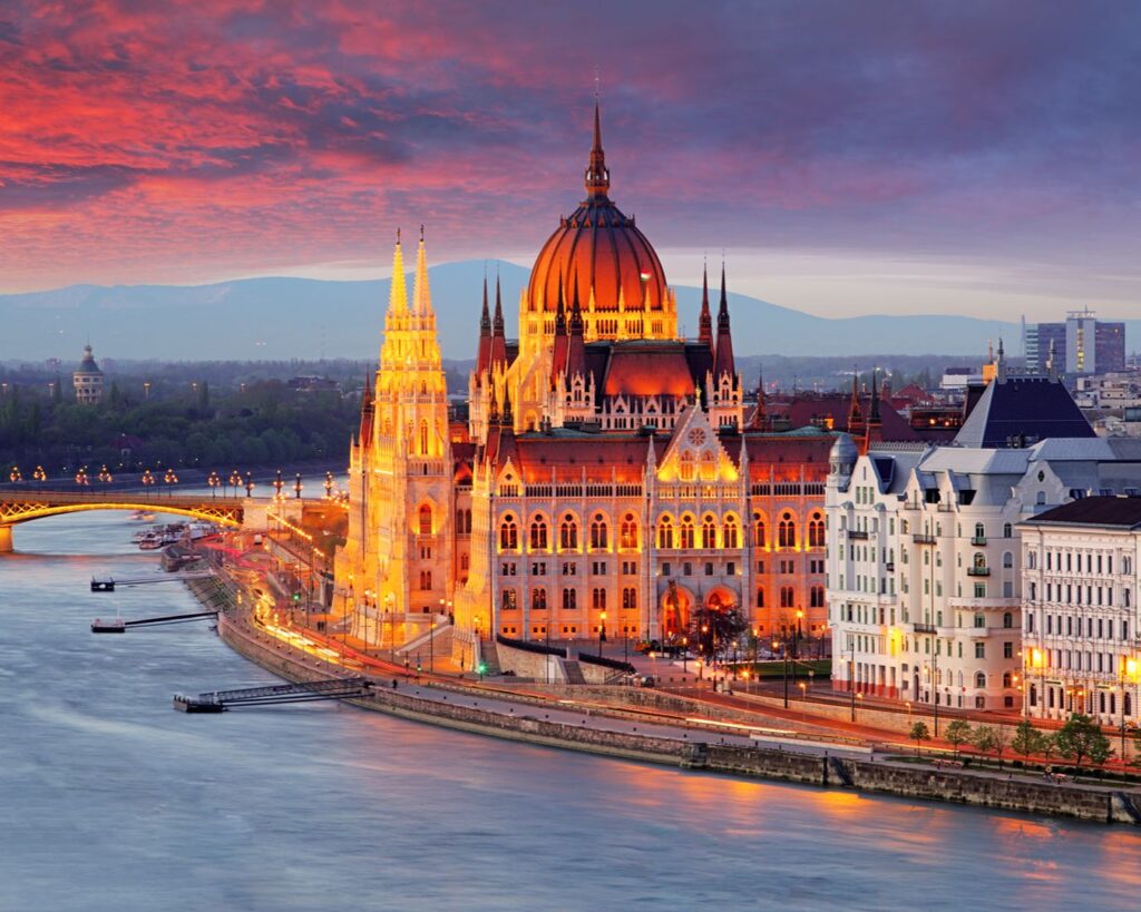 Edifício do Parlamento de Budapeste iluminado ao pôr do sol à beira do Rio Danúbio