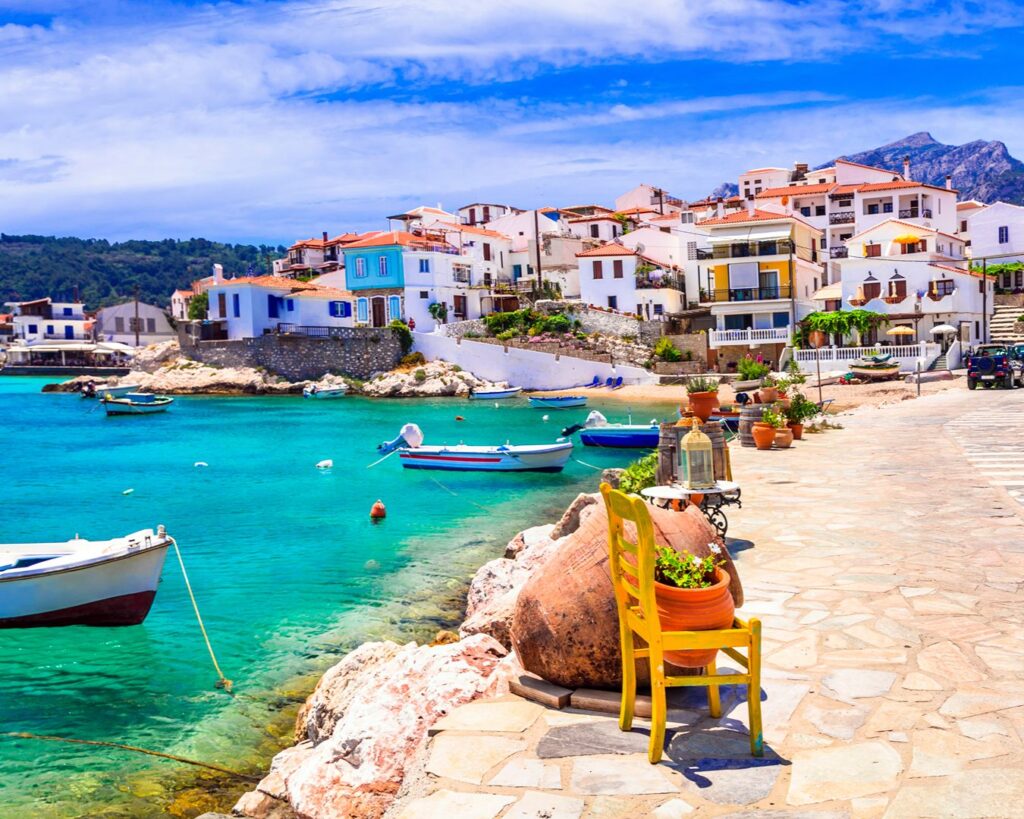 Cadeira amarela em calçadão de pedra à beira-mar na vila de Kokkari, ilha de Samos, Grécia