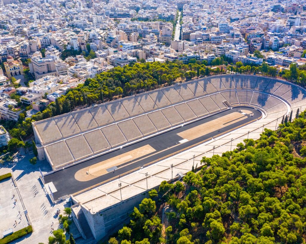 Vista aérea do histórico Estádio Panatenaico de mármore em Atenas cercado por parque e área urbana
