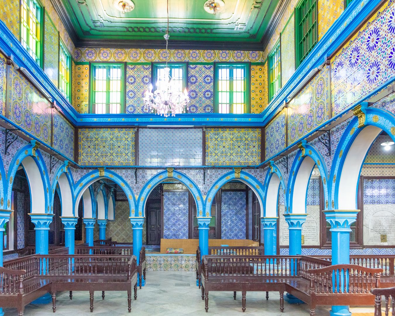 Interior da Sinagoga de El Ghriba em Djerba com arcos azuis decorados e mosaicos coloridos de azulejos