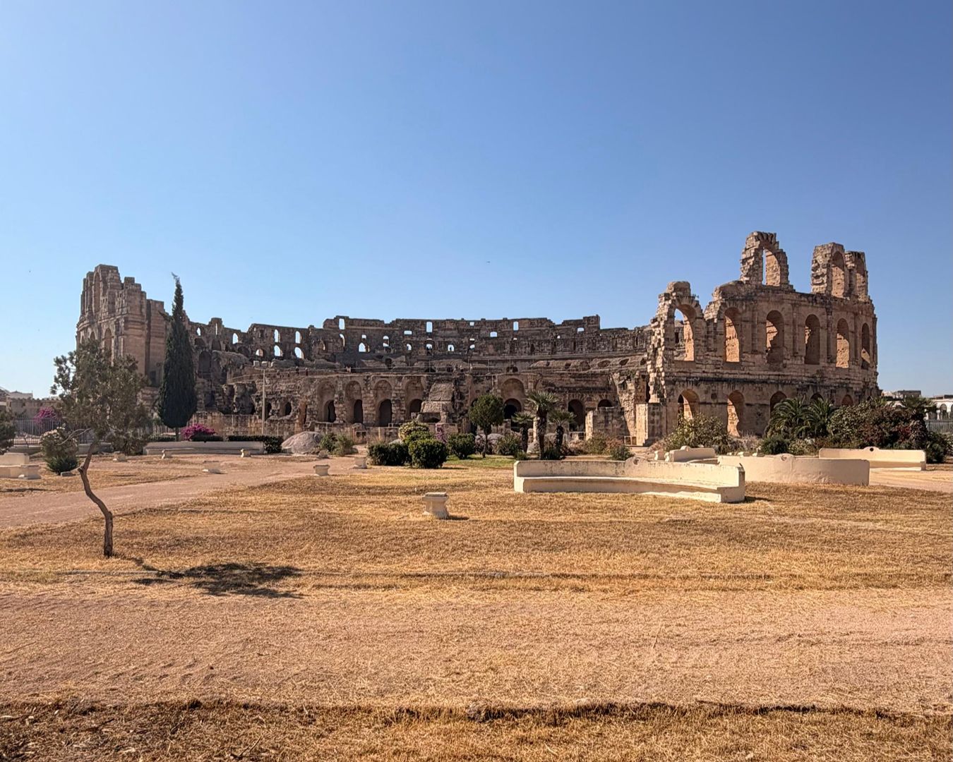 Vista distante das ruínas do grande Anfiteatro Romano de El Jem sob céu azul limpo, na Tunísia