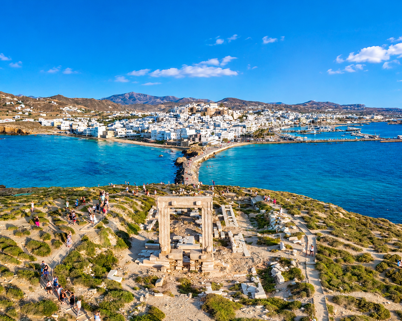 Vista aérea do Portara, o antigo Templo de Apolo na Ilha de Naxos, com o caminho de pedra e a cidade ao fundo cercada pelo mar turquesa